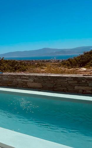 a swimming pool with a brick wall and the ocean at Spiti su in Paros - Naousa Piscina Privata in Kampos Paros