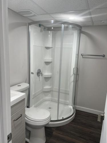 a white bathroom with a shower and a toilet at Guest suite in Transcona in Winnipeg
