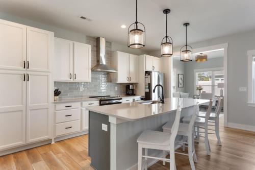 a kitchen with white cabinets and a kitchen island with chairs at 5081 - Sound of the Cs in Kill Devil Hills
