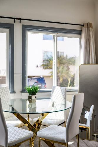 a dining room with a glass table and white chairs at 2BR Luxury Getaway Mins to Beach Arcade & Games in Manhattan Beach