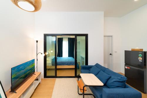 a living room with a blue couch and a bedroom at Homely Home Khao lak in Khao Lak