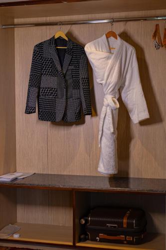 a shelf with clothes and a suit and a suitcase at The Lalita Grand Mathura- Vrindavan in Mathura