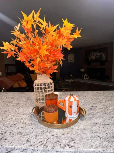 a vase with orange flowers and two cups on a table at Sunshine Oasis Home in Fayetteville