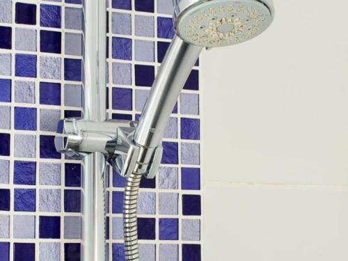 a shower head in a bathroom with blue tiles at Thalassa Hotel in Koh Tao