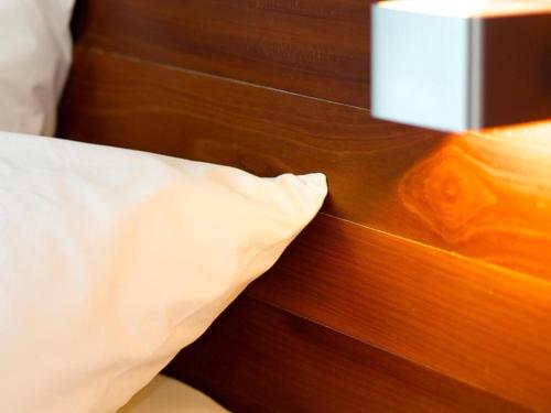 a bed with a white pillow next to a wooden wall at Thalassa Hotel in Koh Tao