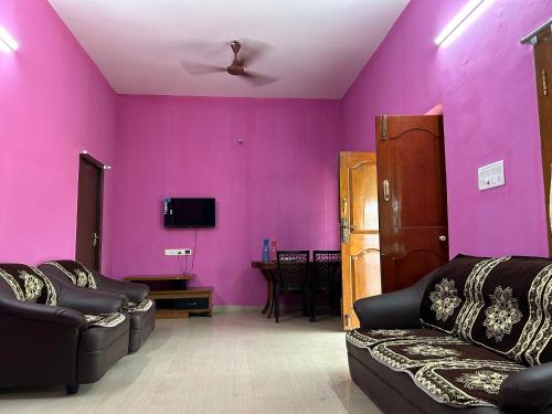 a living room with purple walls and black furniture at Chillaxx Retreat in Yercaud