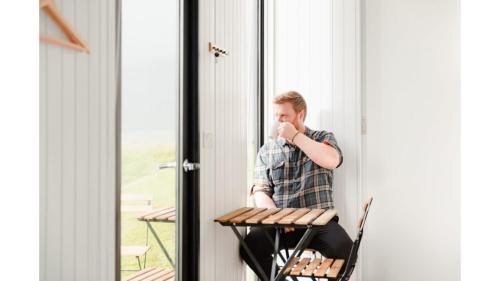 a man sitting in a chair drinking a cup of coffee at The Coast 1 by Tiny Away in Birchfield