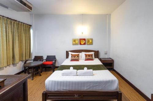 a hotel room with a bed and a table and chairs at Miami Hotel in Chiang Mai