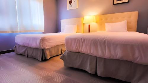 a hotel room with two beds and a window at Jeju EQ Stay in Jeju