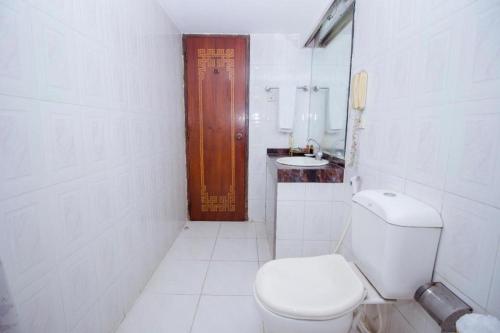 a white bathroom with a toilet and a sink at Hotel De Crystal Crown in Dhaka