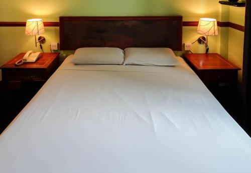 a large white bed with two night stands and two lamps at Four Chain View Hotel in Singapore