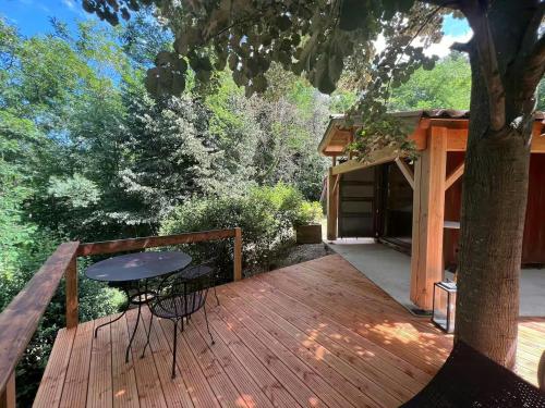 une terrasse en bois avec une table et un arbre dans l'établissement Modern Container In Saint-Jean-Du-Gard, à Saint-Jean-du-Gard