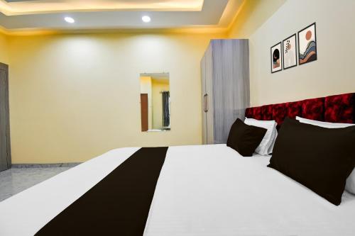 a bedroom with a large white bed with black pillows at Super Townhouse Taramandal Near Sahara States in Bhauvāpār