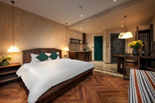 a bedroom with a large white bed and a kitchen at Tranquility Suites Westlake in Hanoi