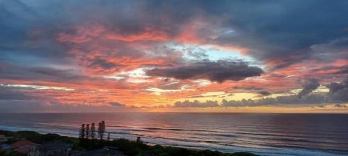 a sunset over the ocean with a cloudy sky at Bayview Guest House in Amanzimtoti
