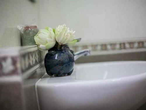 素可泰Wake Up at Muang Kao Boutique Hotel的花朵花在柜台上的蓝色花瓶