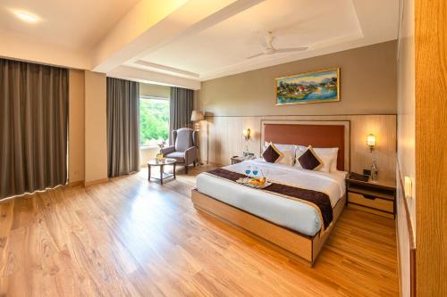 a hotel room with a bed and a chair at The Lalita Grand Mathura- Vrindavan in Mathura