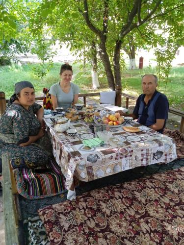 un gruppo di persone seduti intorno a un tavolo con cibo di Porasht homestay a Farish