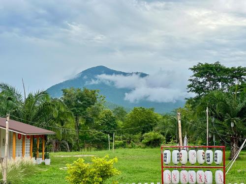 a house with a fence with a mountain in the background at สวนปาล์มการ์เด้นโฮม เชียงคาน Suanpalm Garden Home Changkhan in Chiang Khan