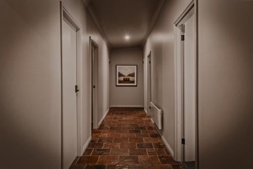 a hallway with a tile floor and a painting on the wall at The Maple Lodge with Alpacas, Goats, Boars, Ducks & Chickens Farm Stay with Outdoor Pizza Oven in Robertson