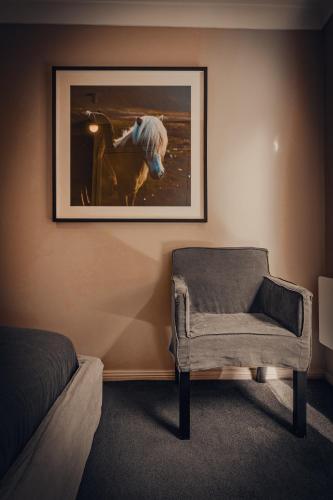 a room with a chair and a picture on the wall at The Maple Lodge with Alpacas, Goats, Boars, Ducks & Chickens Farm Stay with Outdoor Pizza Oven in Robertson