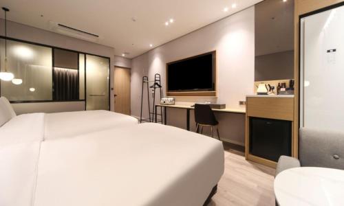 a hotel room with a white bed and a kitchen at Busan Myeongji Ciel Ocean Hotel in Busan