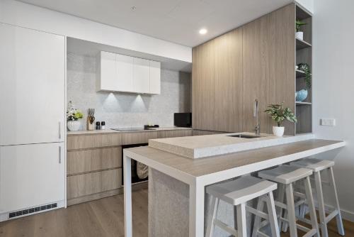 Una cocina con una gran isla con taburetes de bar. en Charming 1-Bed with Rooftop Access & Parking, en North Fremantle