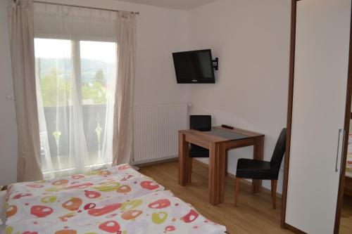 a bedroom with a bed and a desk and a television at Appartements Bürger in Krumpendorf am Wörthersee