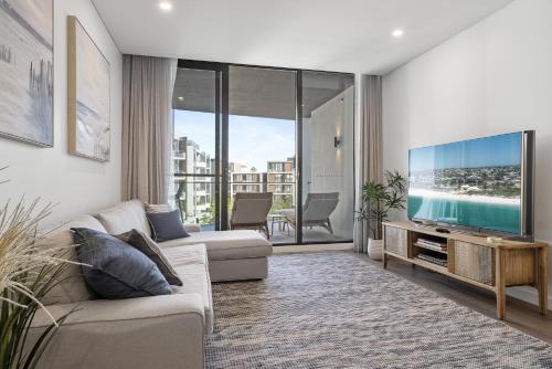 Una sala de estar con un sofá y un televisor de pantalla plana. en Cosmopolitan 1-Bed - Fremantle Beach Front, en North Fremantle