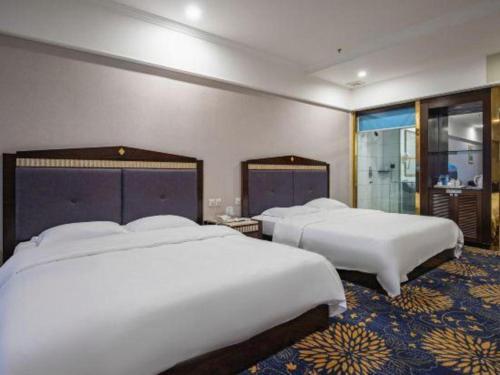 two beds in a hotel room with two bedsskirts at Zhongshan Hui Quan Hotel in Zhongshan