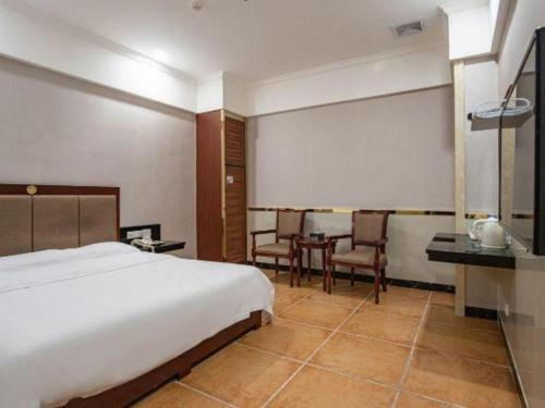 a bedroom with a bed and a table and chairs at Zhongshan Hui Quan Hotel in Zhongshan