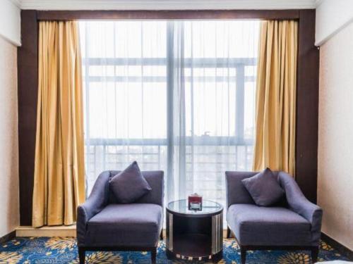 a room with two chairs and a table and a large window at Zhongshan Hui Quan Hotel in Zhongshan