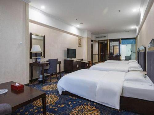 a hotel room with four beds and a desk and a television at Zhongshan Hui Quan Hotel in Zhongshan