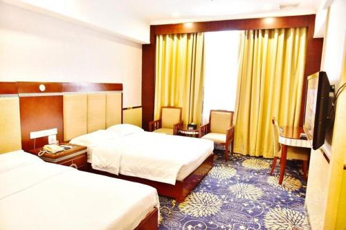 a hotel room with two beds and a television at Zhongshan Hui Quan Hotel in Zhongshan