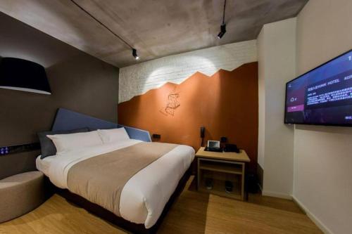 a bedroom with a bed and a flat screen tv at YUNIK-Shanghai Zhongshan Park Yan'an Xi Road in Shanghai