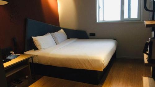 a bedroom with a bed with a white bedspread and a window at YUNIK-Shanghai Zhongshan Park Yan'an Xi Road in Shanghai
