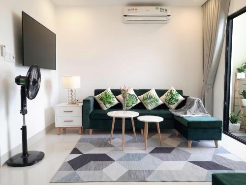 a living room with a green couch and a table at Vina Apartment- Căn hộ trung tâm Huế in Thôn Trường Giang