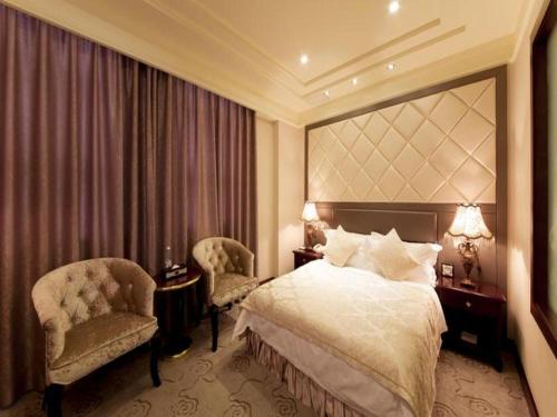 a hotel room with a bed and two chairs at Chengdu Haotian Guotai Hotel in Chengdu