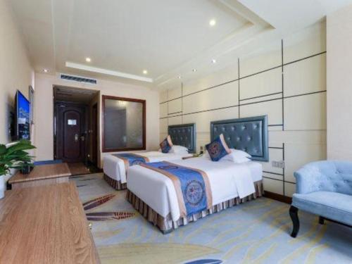 a hotel room with two beds and a chair at Chengdu Haotian Guotai Hotel in Chengdu