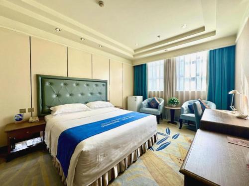 a hotel room with a large bed and two chairs at Chengdu Haotian Guotai Hotel in Chengdu