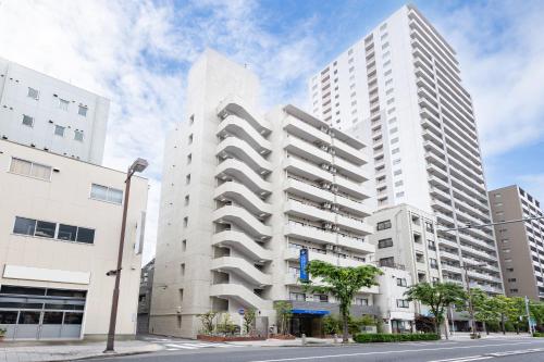a tall white building on a city street at HOTEL MYSTAYS Nippori in Tokyo