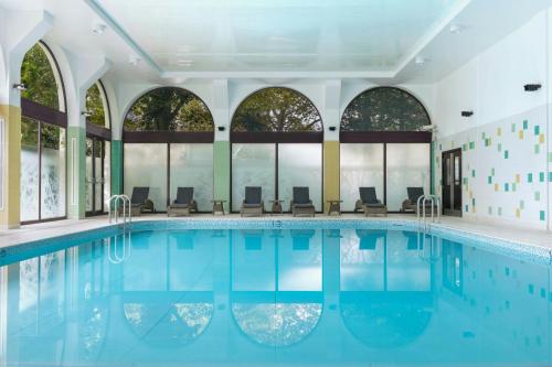 a swimming pool with chairs in a building with windows at London Marriott Hotel Regents Park in London