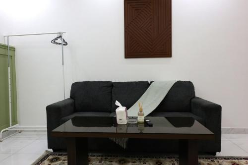 a living room with a black couch and a table at A spacious apartment with a full kitchen in Al Madinah