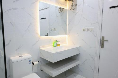 a white bathroom with a sink and a mirror at A spacious apartment with a full kitchen in Al Madinah