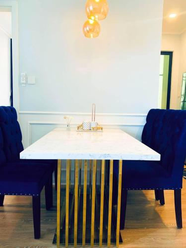 a dining room table with two blue chairs and a white counter at Vina Apartment- Căn hộ trung tâm Huế in Thôn Trường Giang