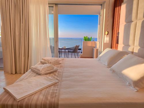 a bedroom with a large bed with a view of the ocean at Theo Beach Hotel Apartments in Rethymno Town