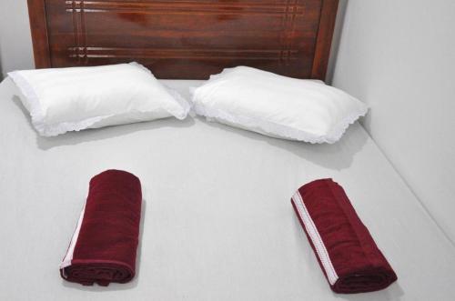 two white pillows and a pair of red slippers at Sun Up Hotel in Katunayake