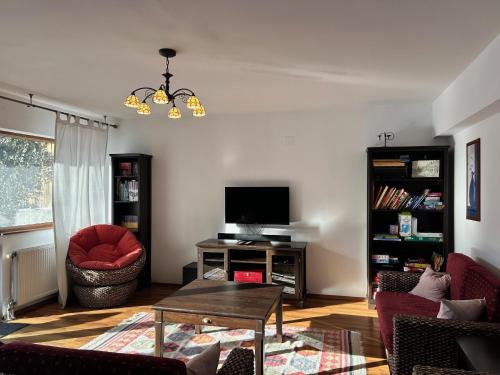 a living room with a red chair and a television at Cheerful 4-bedroom & kids friendly home in Predeal