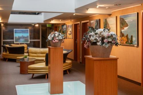a lobby with two potted plants on wooden pillars at Art City Inn in Vilnius