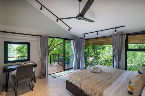 a bedroom with a bed and a desk and windows at Payana Kampot in Kampot